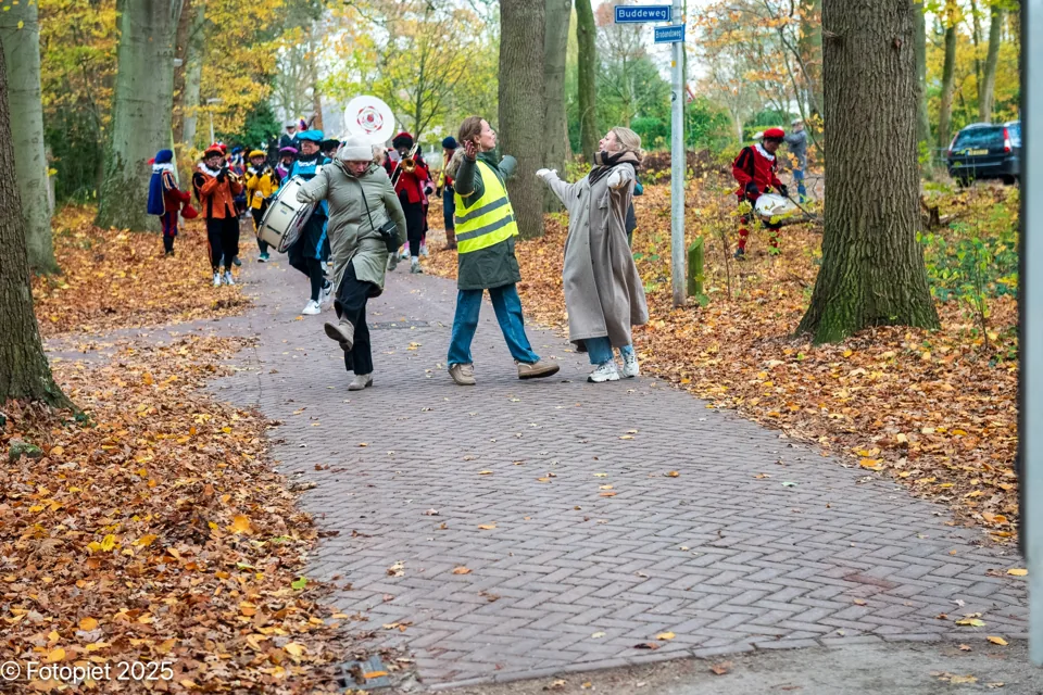 De optocht loopt tussen herfstbomen over een pad in 2025.