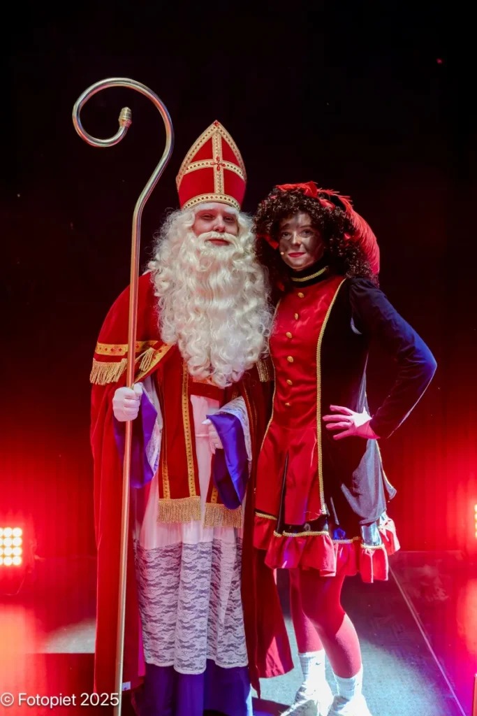 Sinterklaas en een Piet staan samen op het podium in 2025.